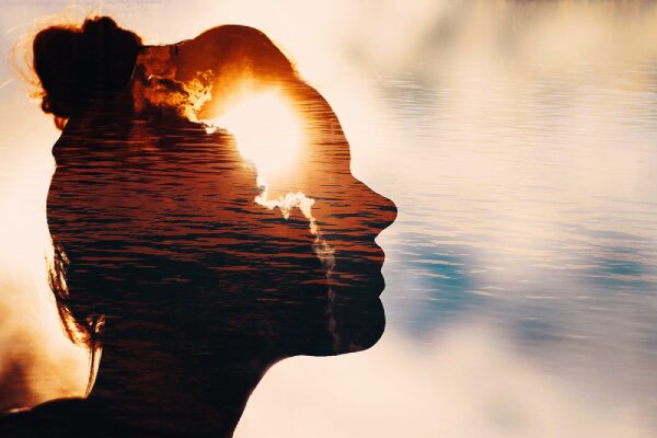 Woman profile double exposure with sunburst and water