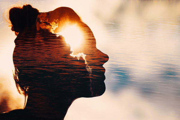 A silhouette of a person with a sunset and water